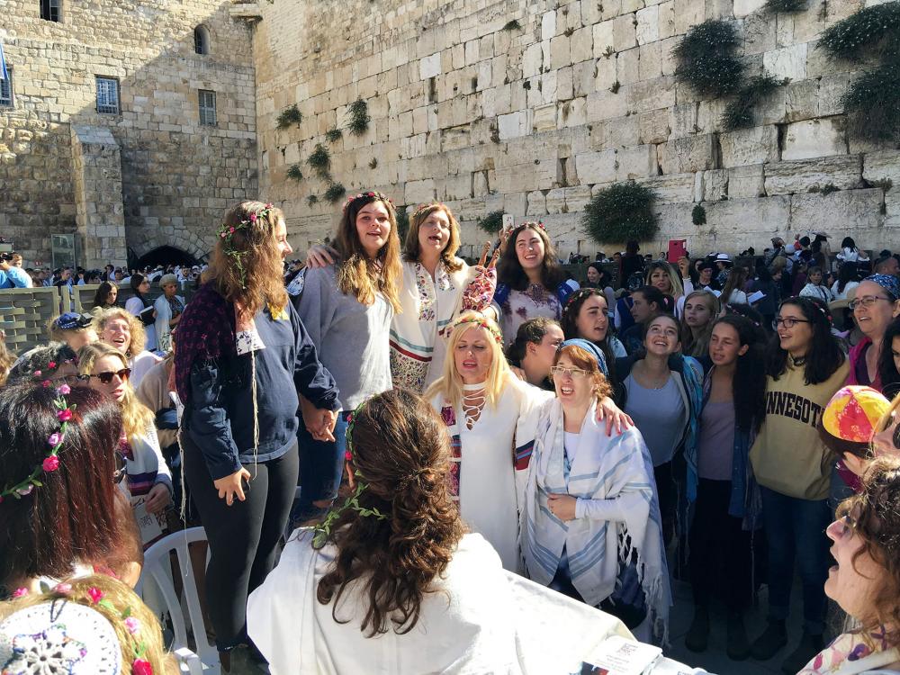 Singing women at the Wailing Wall, partly with wreaths of flowers and prayer shawls