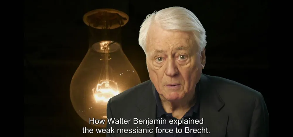 Ein wei&szlig;haariger Mann im Vordergrund, im Hintergrund eine riesige Gl&uuml;hbirne.
