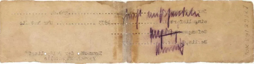 Rückseite eines vergilbten Zettels in extremem Querformat. Einige Buchstaben des Schreibmaschinentextes der Vorderseite sind als spiegelverkehrter Abdruck sichtbar, außerdem eine handschriftliche Notiz