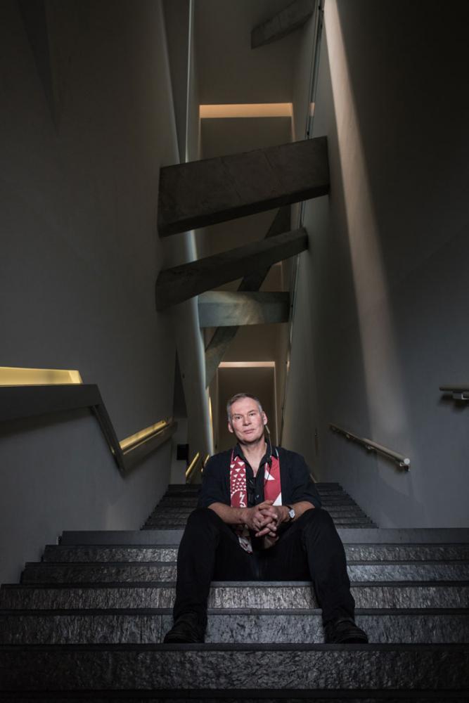 A middle-aged man sits on stairs in the Jewish Museum Berlin