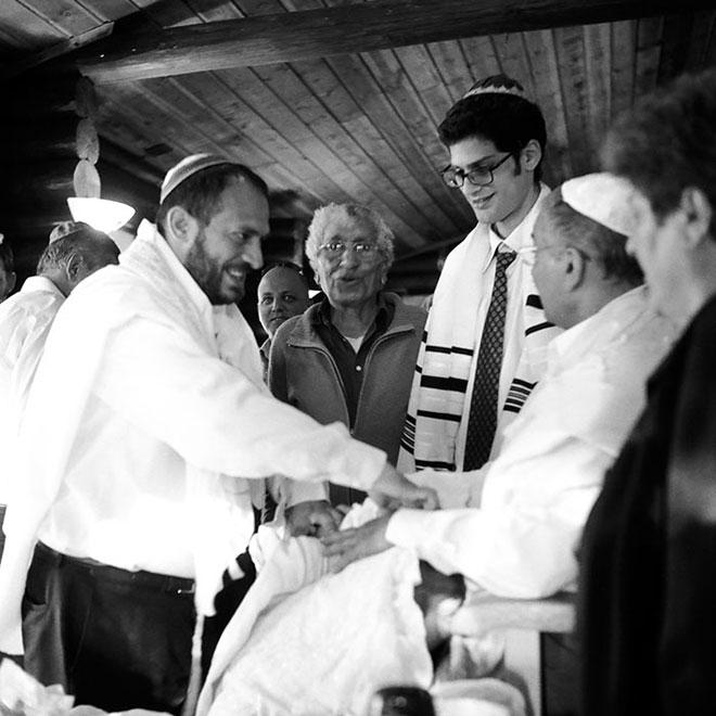 Black and white photography: Yahir lies on his godfather’s lap, father and grandfather are watching him