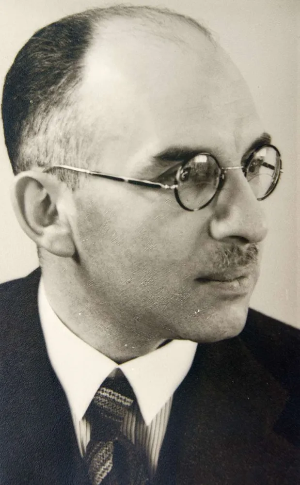 Black-and-white portrait of a man with spectacles, a mustache, and a high forehead
