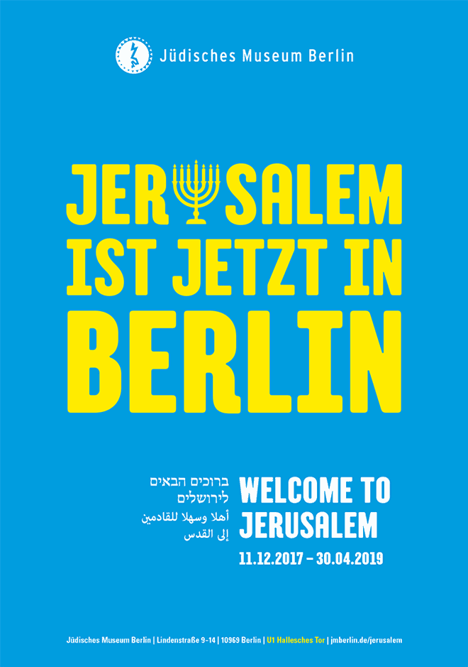 Ausstellungsplakat mit Aufschrift &quot;Jerusalem ist jetzt in Berlin&quot; in gelben Buchstaben auf blauem Hintergrund. Der Buchstabe 'u' in Jerusalem hat die Form einer Menora
