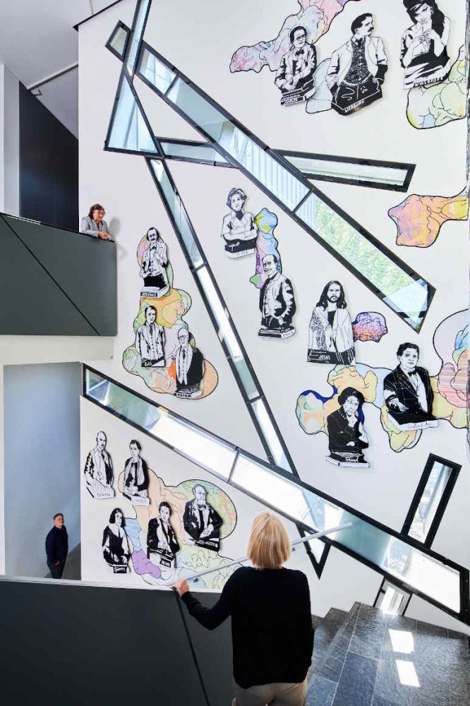 Treppe mit Personen und mit Illustrationen von Personen an der Wand,