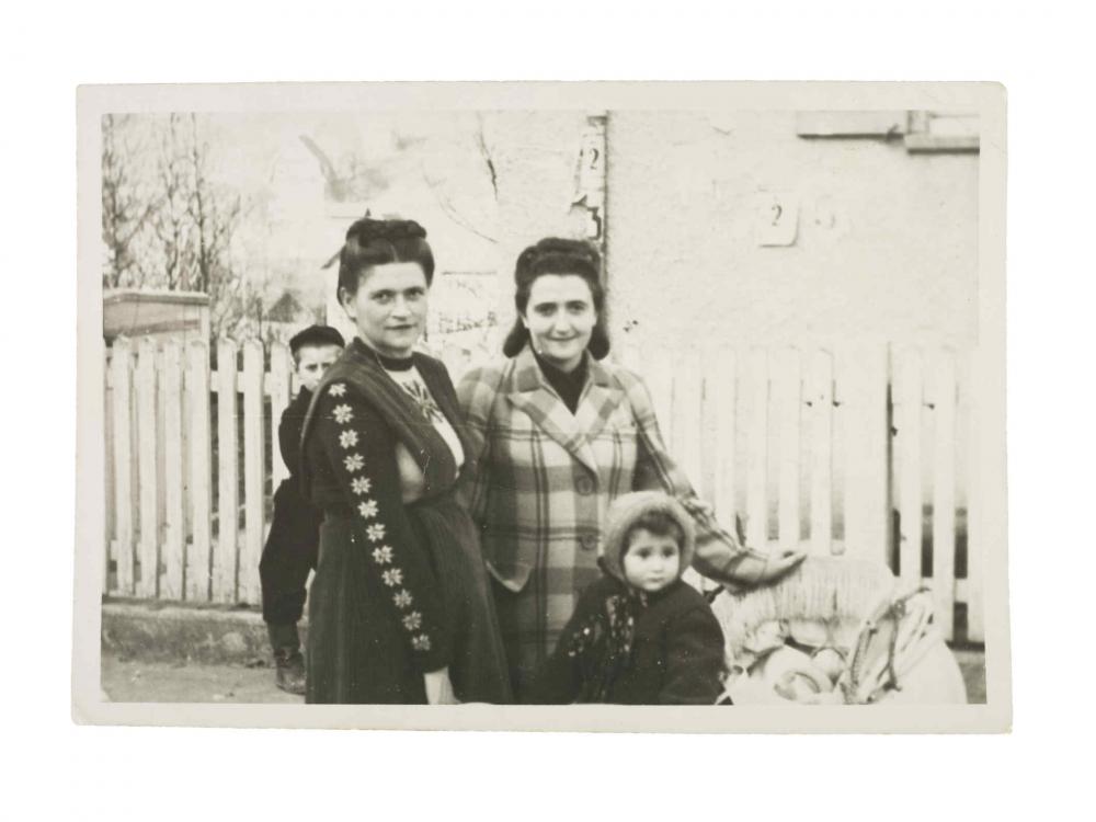  Photo of two women and two children in front of a picket fence