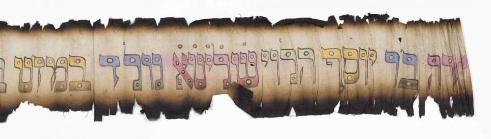 Angebrannter Streifen Papier mit bunten hebräischen Buchstaben