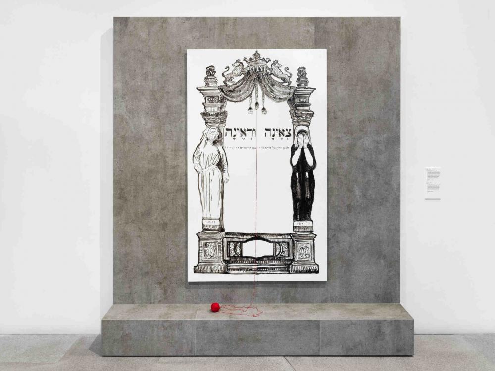 Ausstellungsmöbel aus Beton mit einem schwarz-weiß Bild und einem roten Wollknäuel