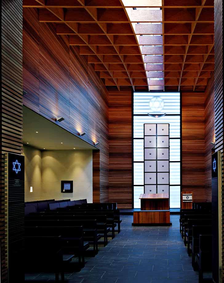 Interior view of the synagogue, wood-panelled wall, Torah shrine is illuminated in blue