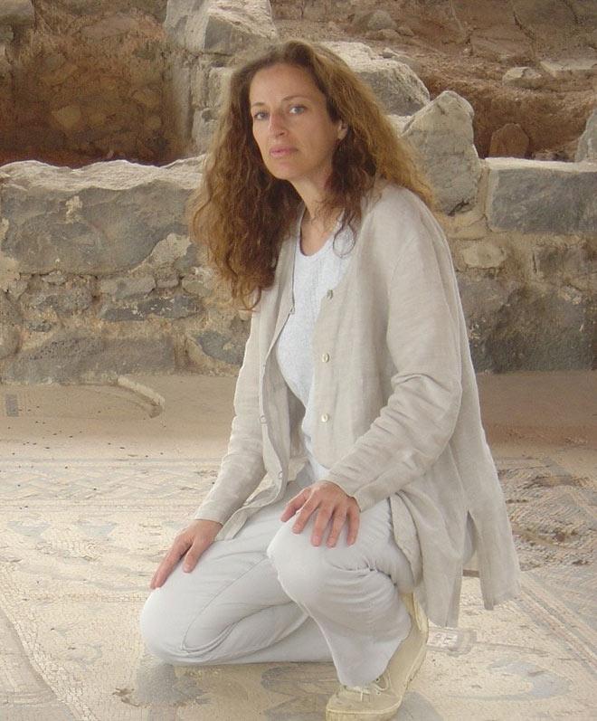 A woman on a mosaic floor in front of ruins