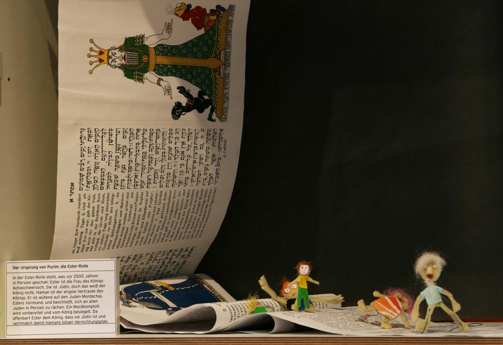 Cloth puppets walking on a parchment scroll with writing and illustrations