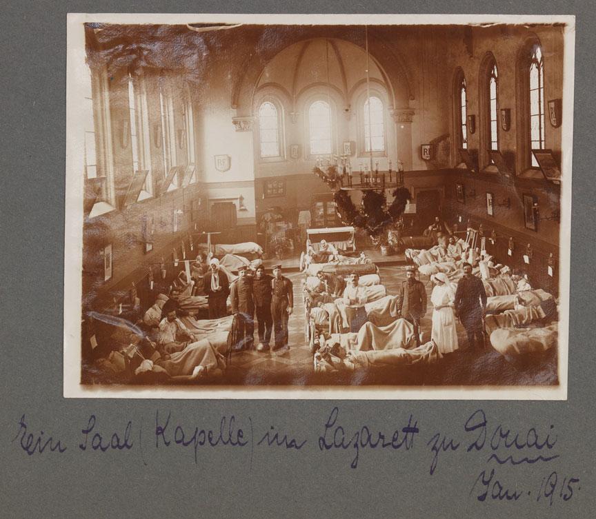 Schwarz-weiß Fotografie eines Krankensaals mit mehreren Personen eingerichtet in einer Kirchenkapelle.