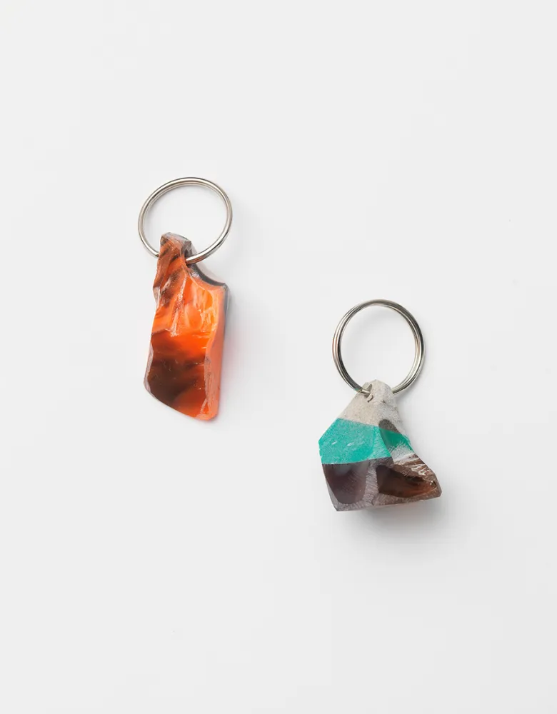 Two small brightly colored mineral or rock like objects with a keychain ring in each one