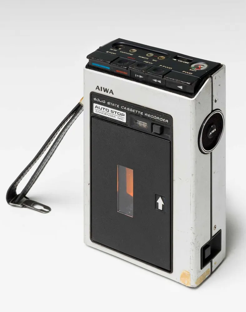 Fotografie eines Audioaufnahmegeräts für Tonkassetten mit schwarzer Lederschlaufe der Marke AIWA aus den 1970er Jahren. 
