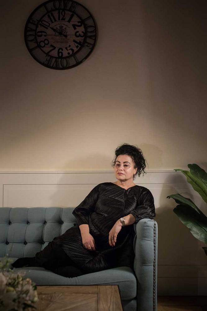 Frau in schwarzem Kleid sitzt auf einem Sofa.