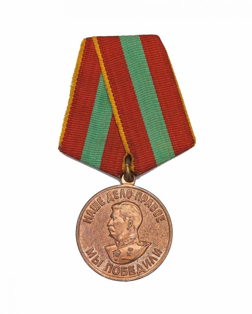 Bronzefarbene Medaille mit einem Reliefbild Stalins und kyrillischer Schrift an einem rot-grün gestreiften Band