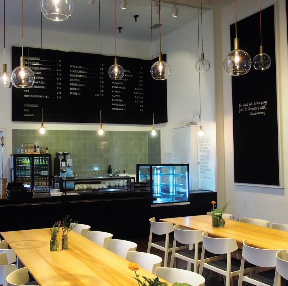 View of the bar of the café with the food counter, in the foreground tables and chairs