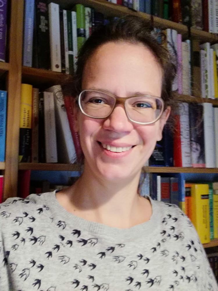 Selfie Marie Naumann in front of a bookshelf