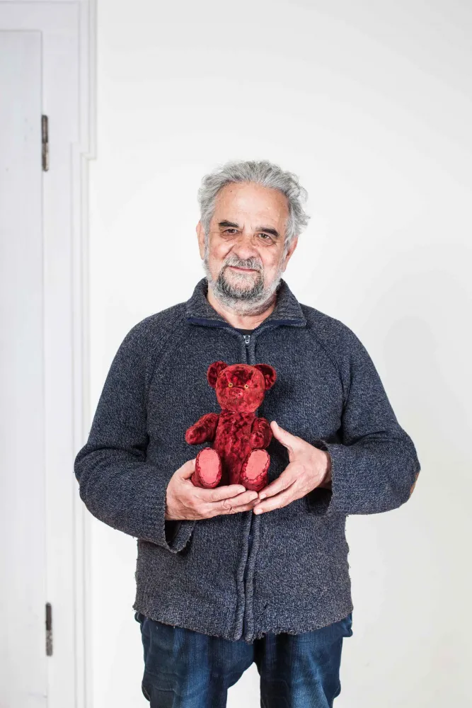 Älterer Herr hält einen roten Teddybären in Händen