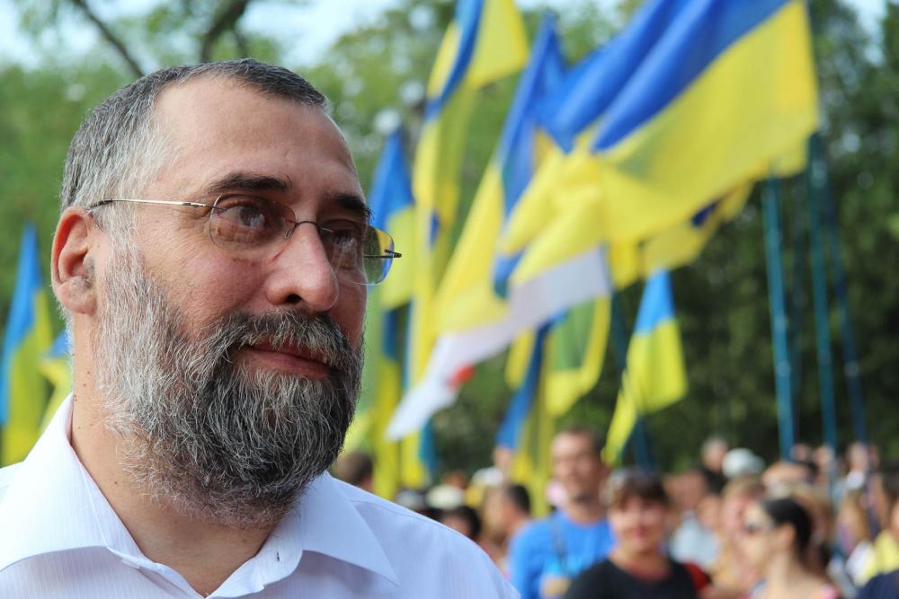  Portrait of Oleg Rostovtsev. Ukrainian flags are flying in the background.