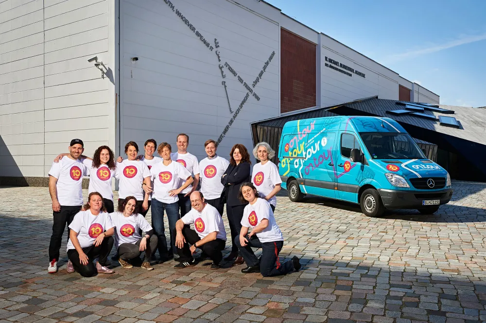 Gruppenfoto mit on.tour-Bus vor der W. M. Blumenthal Akademie mit Mitarbeiter*innen und Guides von „on.tour – Das Jüdische Museum Berlin macht Schule“ mit Programmdirektorin Léontine Meijer-van Mensch
