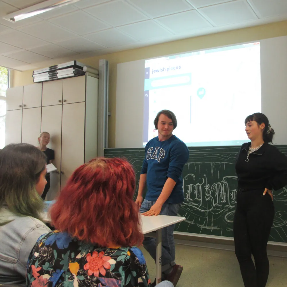 Schüler*innen präsentieren vor einer digitalen Schultafel