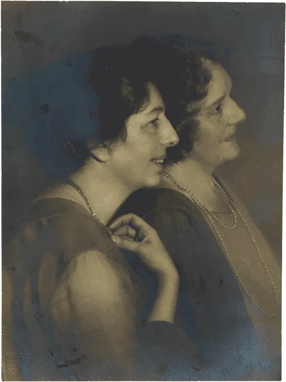 Historical black-and-white photograph of two women in profile leaning against each other.