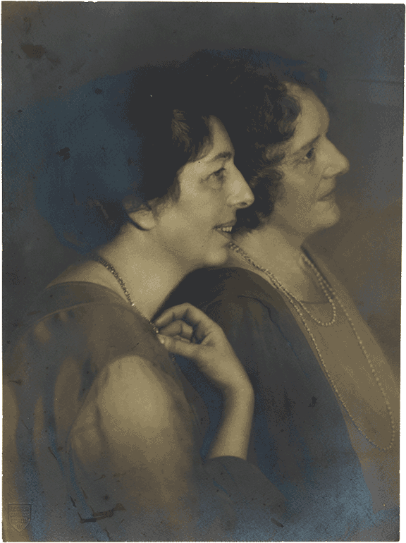 Historical black-and-white photograph of two women in profile leaning against each other.