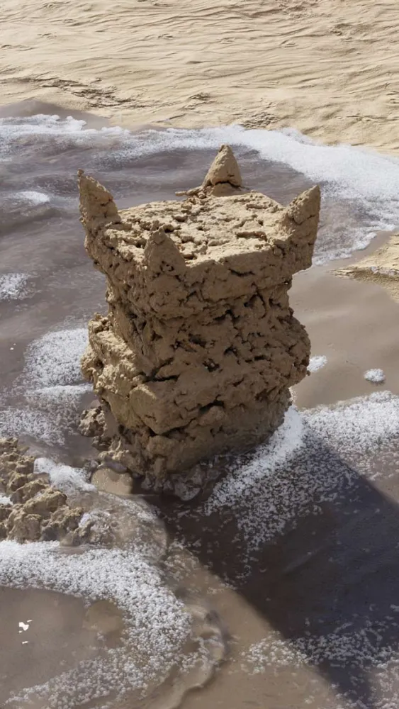 Quadratisch in die Höhe ragender Sandturm am Strand mit vier spitzen Zinnen an den oberen Ecken, von Meerwasser umspült.