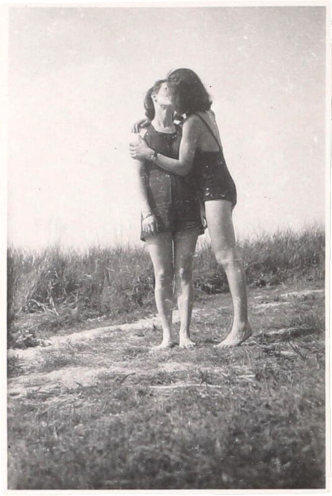 Schwarz-Wieß-Fotografie zweier Frauen im Badeanzug, die sich küssen