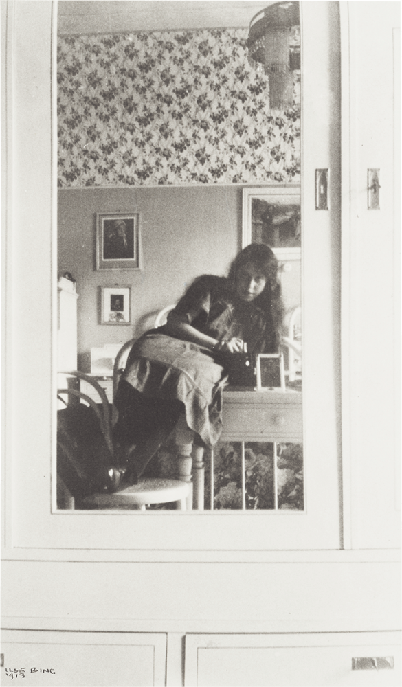 Teenage girl in a mirror attached to the door of a light cabinet