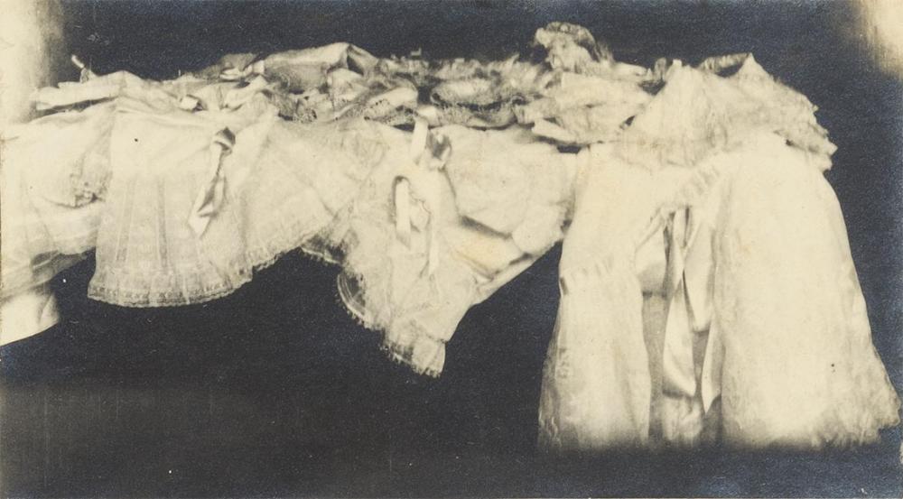 Das Foto zeigt mehrere achtlos abgelegte weiße Unterröcke aus Spitze mit Bändern vor dunklem Hintergrund.