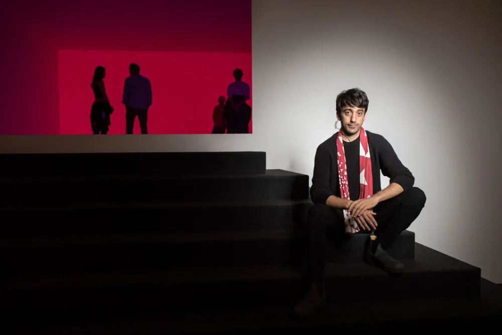 Ein junger Mann sitzt auf der Treppe, die zur Installation „Ganzfeld Aural“ von James Turrell führt