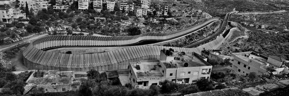 Schwarz-weiß-Foto einer Autobahn, die mit hohen Mauern von den umliegenden Häusern abgeschirmt ist