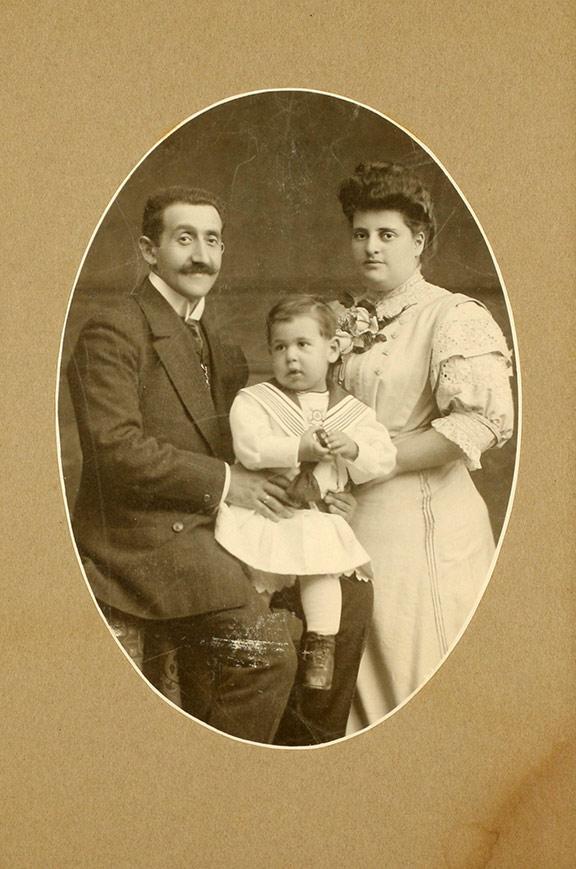 Oval studio photo of a couple with a small child on the father's lap