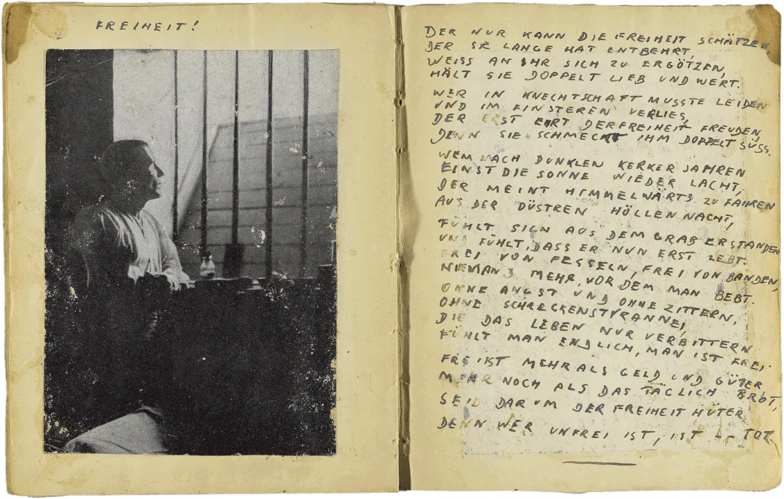Handschriftlich verfasste Doppelseite in Druckbuchstaben mit eingeklebtem Foto eines Mann, der durch die Gitter seiner Zelle schaut, und dem Titel: „Freiheit“.