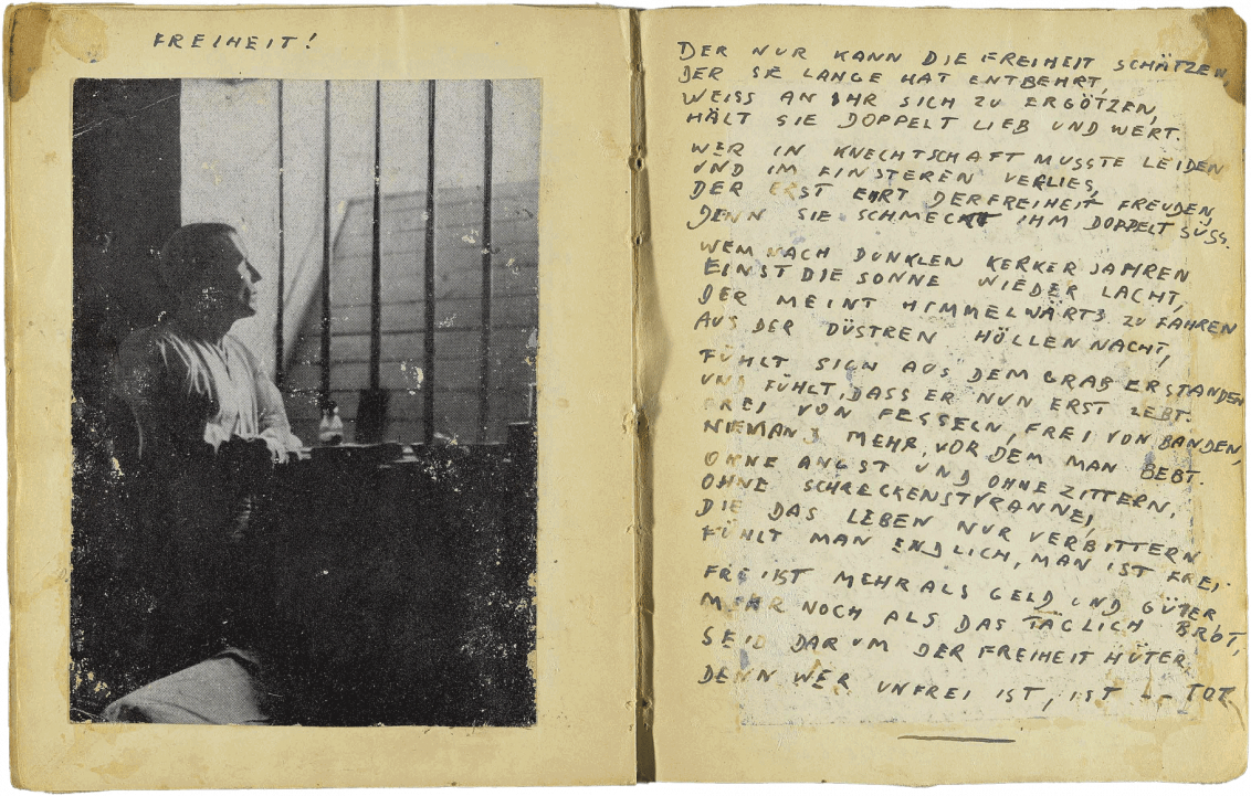 Handschriftlich verfasste Doppelseite in Druckbuchstaben mit eingeklebtem Foto von einem Mann, der durch die Gitter seiner Zelle schaut, und dem Titel: Freiheit.