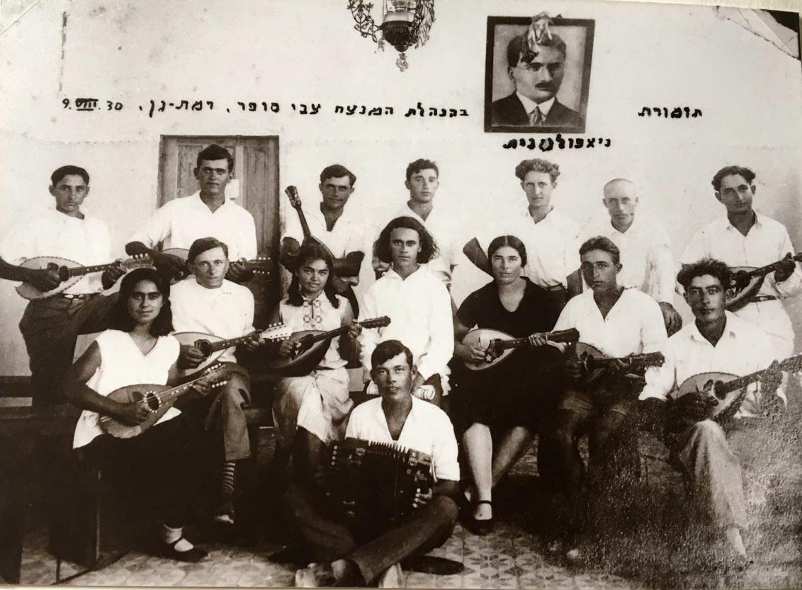 Group photo of 15 musicians with white shirts and mandolins