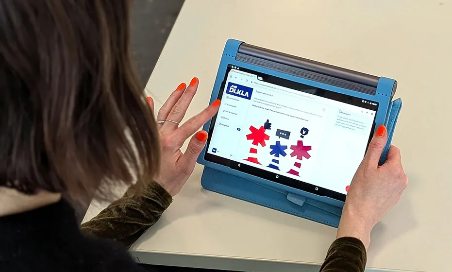 A person from behind holding a tablet with the JMB di.kla application.