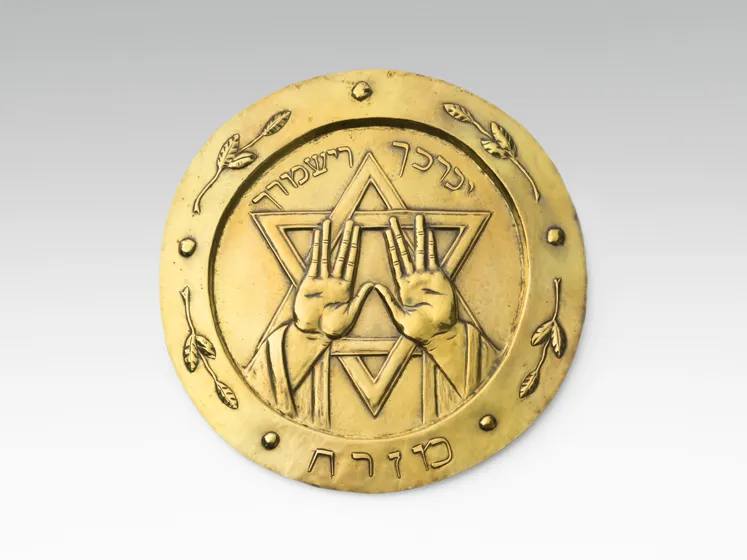 Gold-colored plate with Hebrew script, Star of David and two hands.
