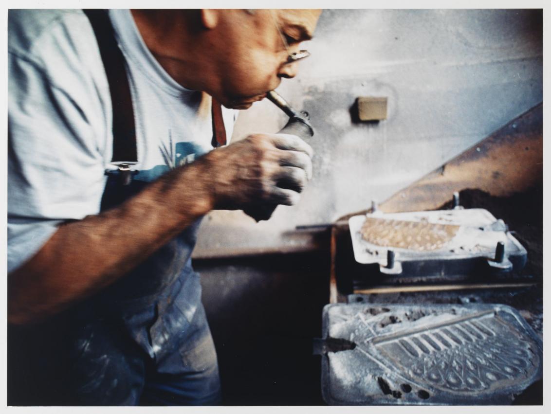 Mr. Ehrlich sprays fine mist of water on the sand mold of the Hanukkah lamp.