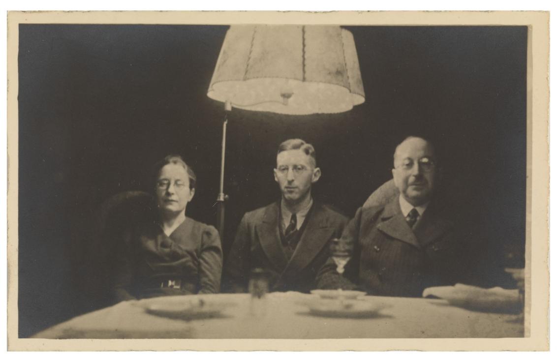 Drei Personen an einem Tisch sitzend unter einem Lampenschirm