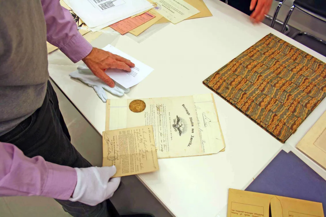 Hands hold old documents and letters.
