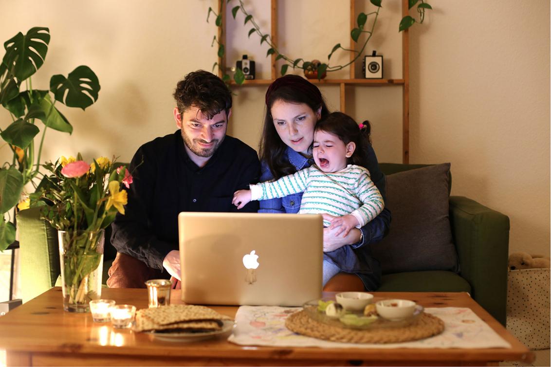 A man, a woman and a crying child sit in front of a laptop
