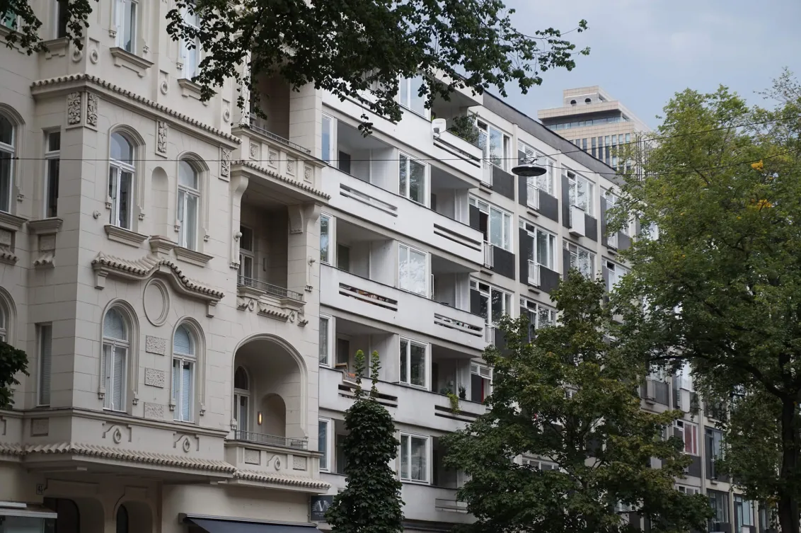 Color photo: Façades of a prewar and a postwar Berlin building, with trees