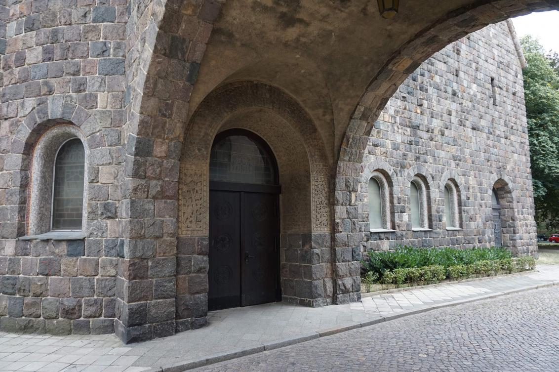 Farbfoto: Eingangsportal einer neoromanischen Kirche aus Granitsteinen