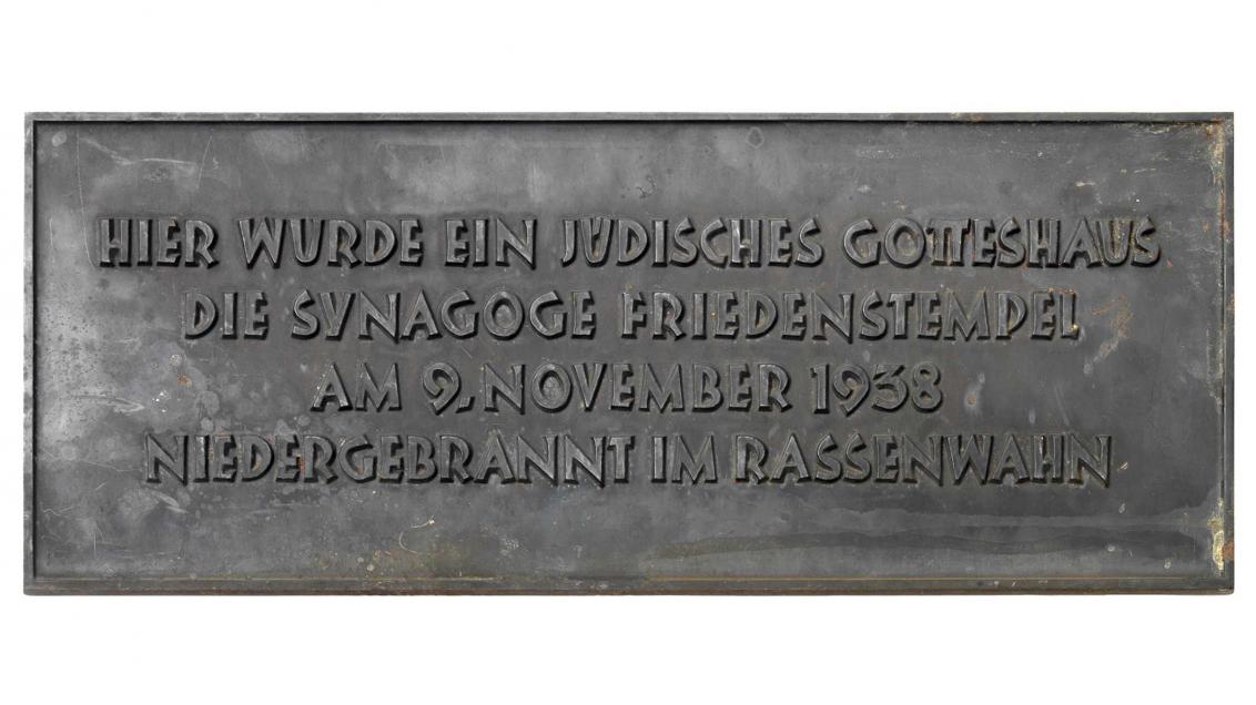 Eine Gedenktafel mit der Aufschrift »Hier wurde ein jüdisches Gotteshaus/ die Synagoge Friedenstempel/ am 9. November 1938/ niedergebrannt im Rassenwahn«
