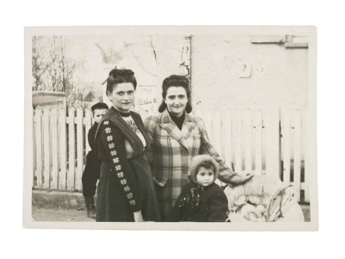  Photo of two women and two children in front of a picket fence