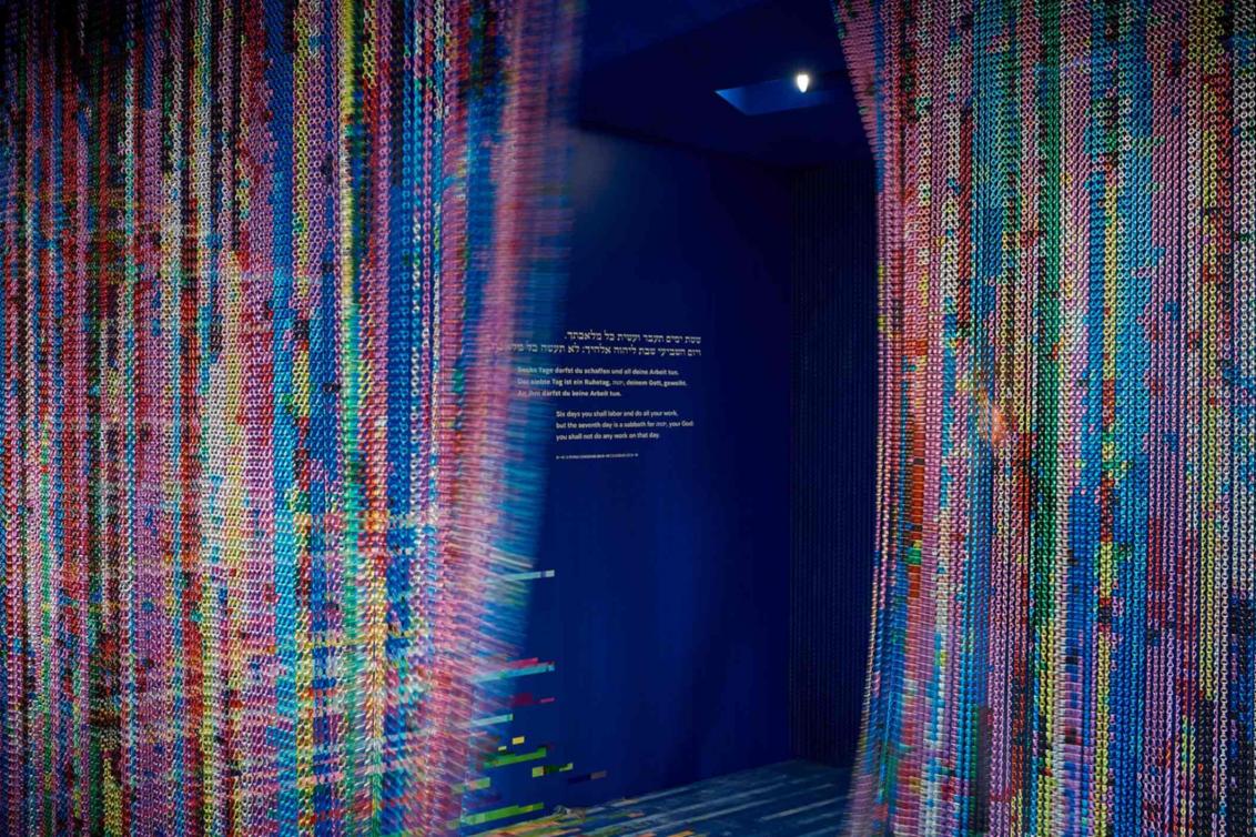 Colorful curtain that is in motion. In the middle is a blue wall with writing