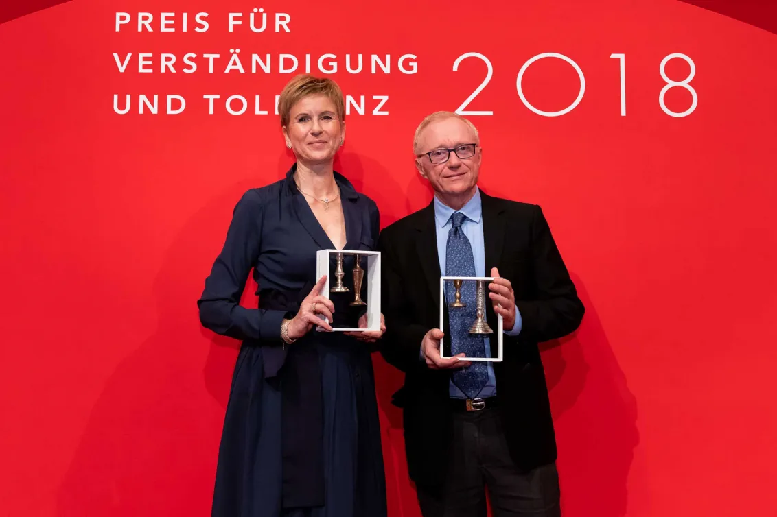 A man and a woman hold the awards to the camera.