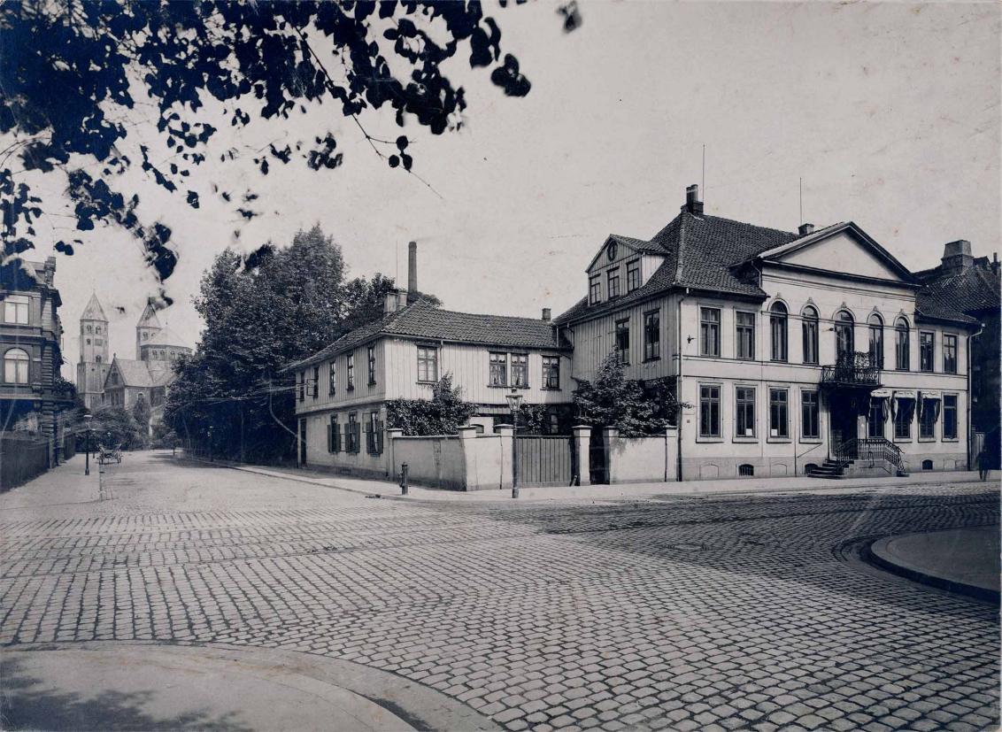 Schwarz-Weiß-Foto eines herrschaftlichen Anwesens auf einem Eckgrundstück.